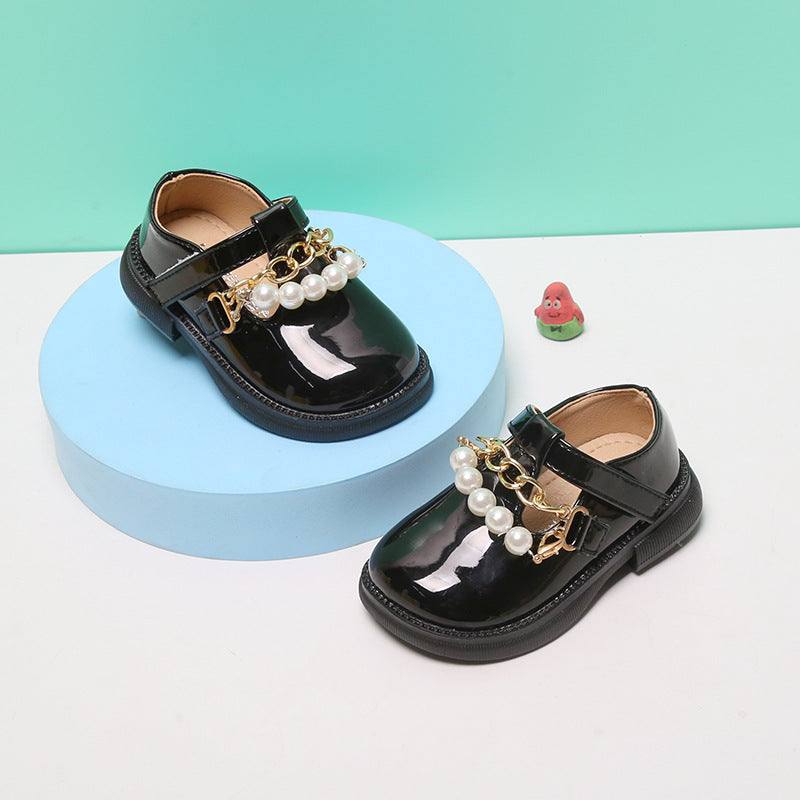 Children's black patent leather princess shoes with pearl embellishments and Velcro closure.