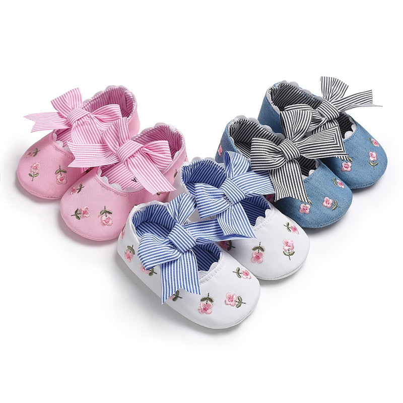 Floral and striped bow baby girls' shoes in pink, white, and blue.
