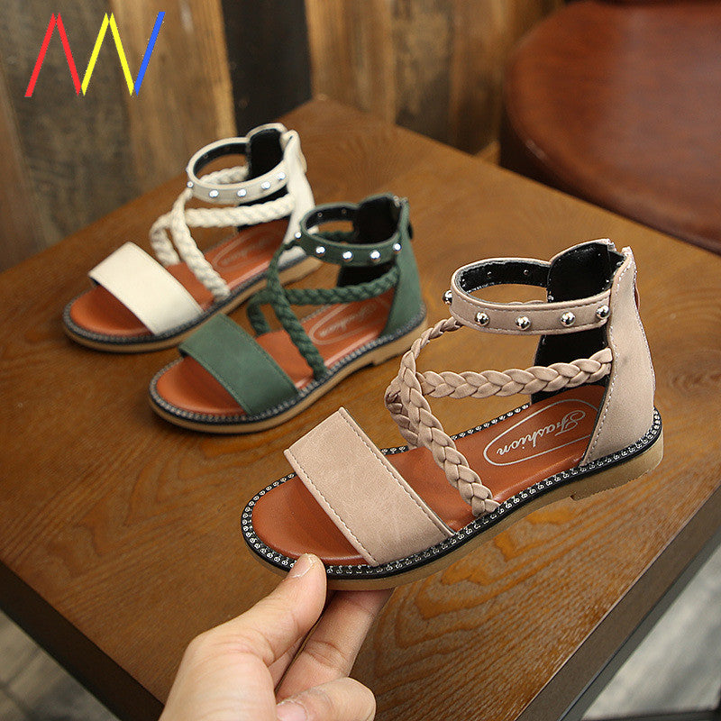 Girls beach sandals with rivet design in white, green, and pink on a wooden surface.