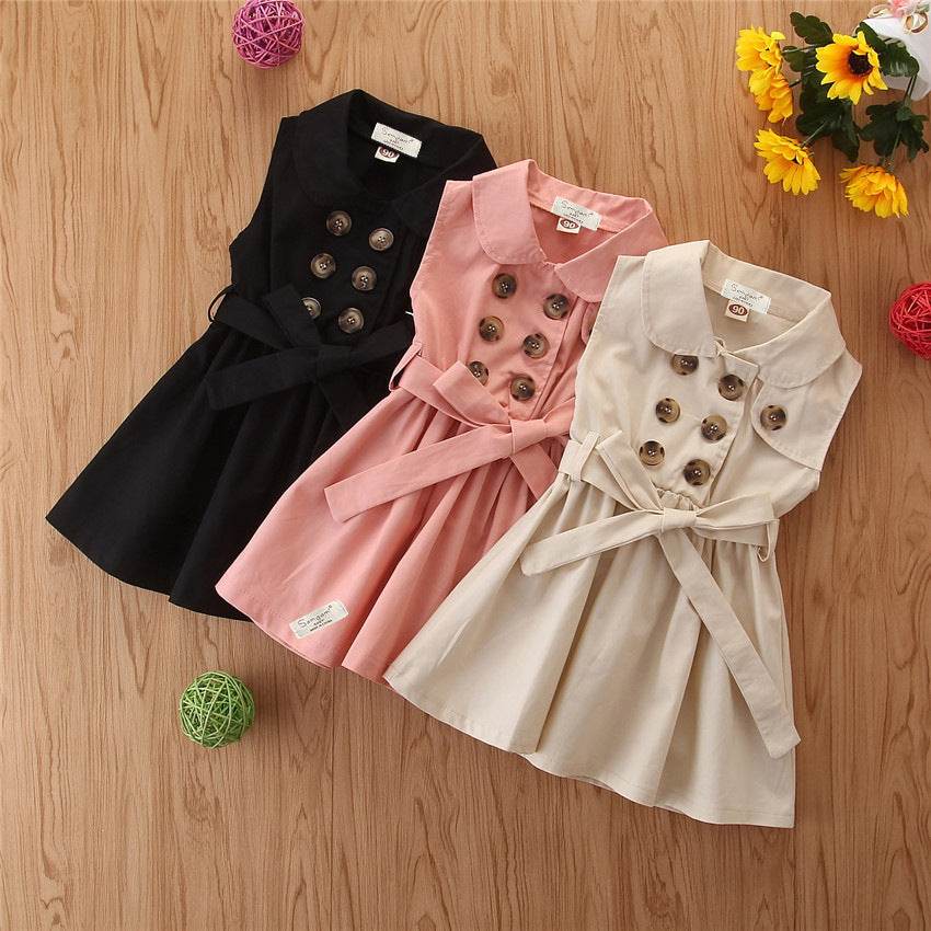 Summer toddler girl casual sleeveless sash button dress in black, pink, and khaki on wooden background.