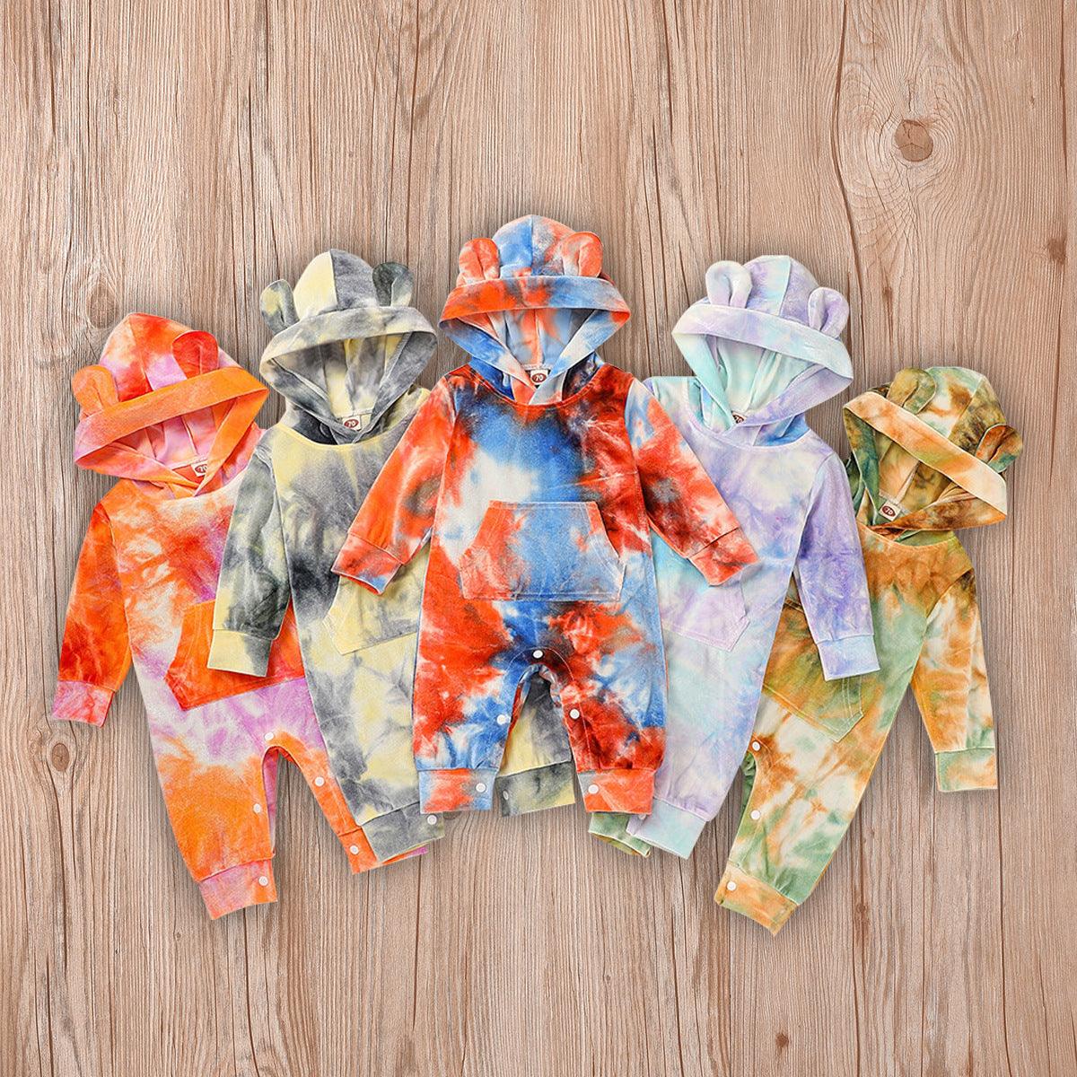 Tie dye hooded baby rompers in vibrant colors on wooden background.