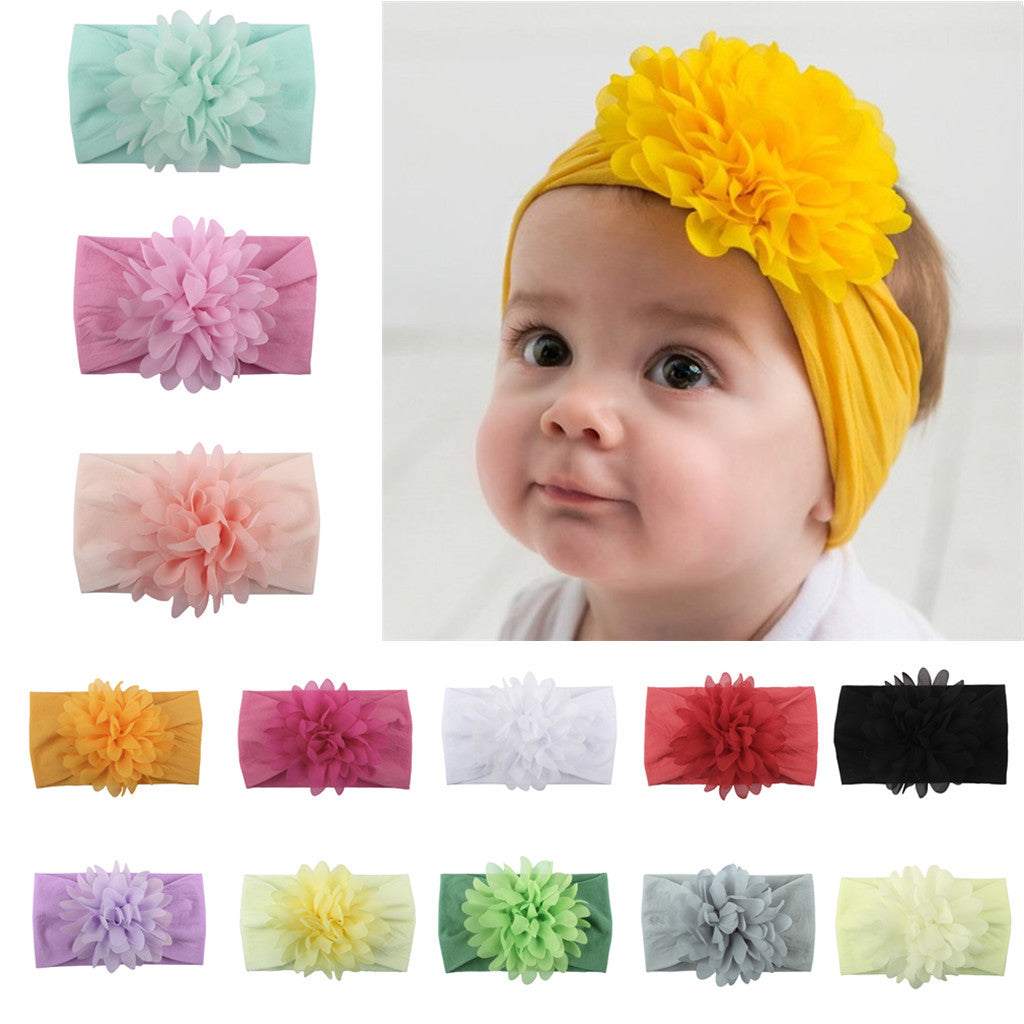 Baby wearing a yellow flower headband surrounded by other colorful flower headbands.