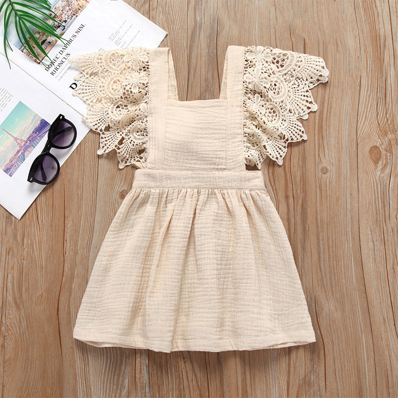 Girl lace suspender dress in apricot color, featuring cotton fabric and intricate lace sleeves, displayed on wooden surface with sunglasses and magazine.