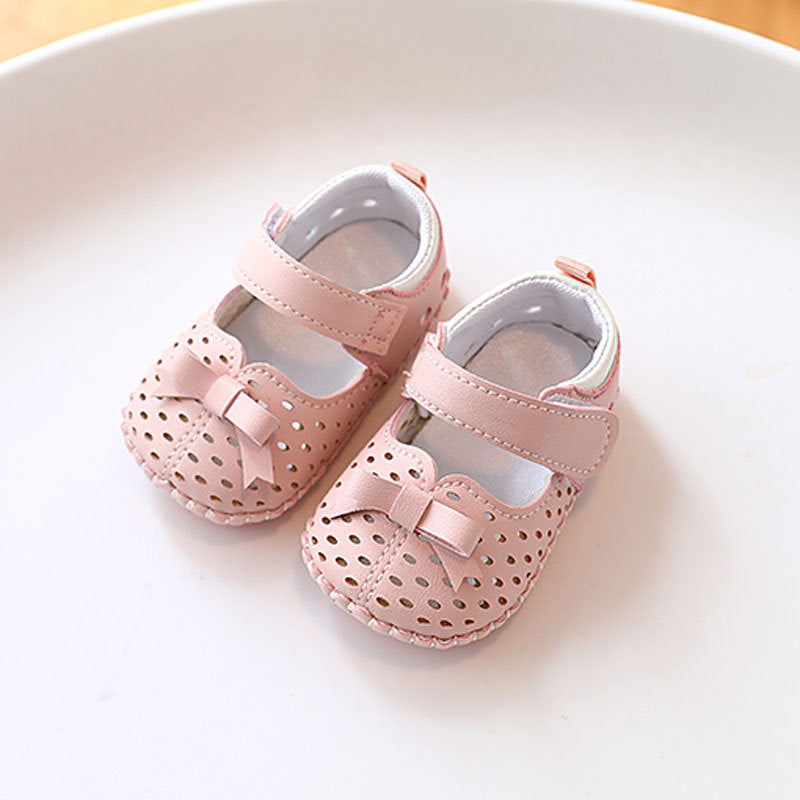 Cute baby girl soft bottom shoes in pink with a bow and Velcro strap, made from synthetic leather.