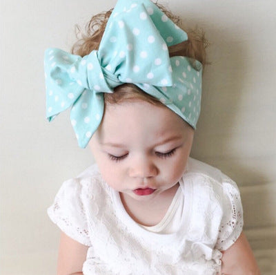 Unisex baby lace bow hair tie in polka dot cloth design.